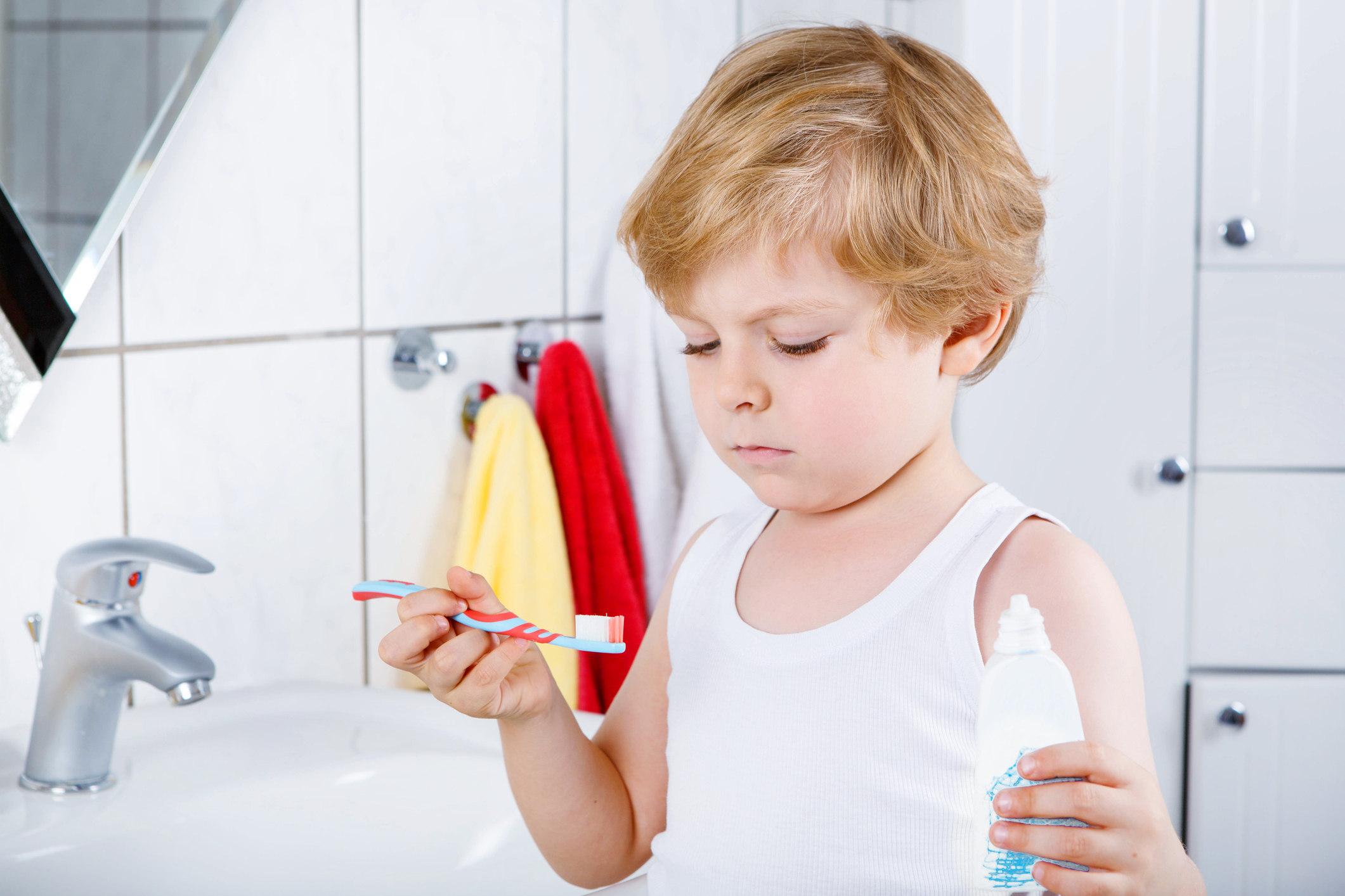 Cute blond kid boy of 2 years learning brushing his teeth in domestic bath. Children learning how to stay healthy.
