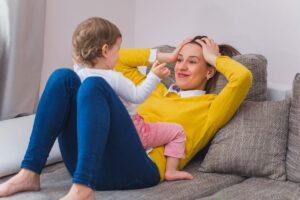 A woman is playing with a baby on the sofa
