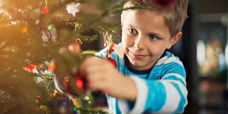 A little boy putting an ornament on the christmas tree