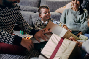A little boy opening his Christmas gift with his parents.