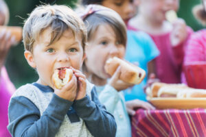 A bunch of kids eating hot dogs