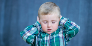 A little boy covering his ears and closing his eyes