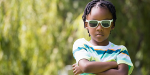A kid crossing his arms while wearing sunglasses